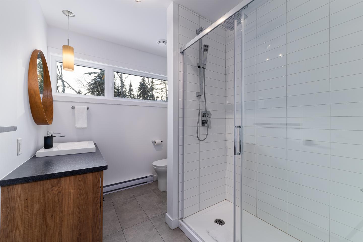 Salle de bain moderne avec douche vitrée et lavabo sur meuble en bois.