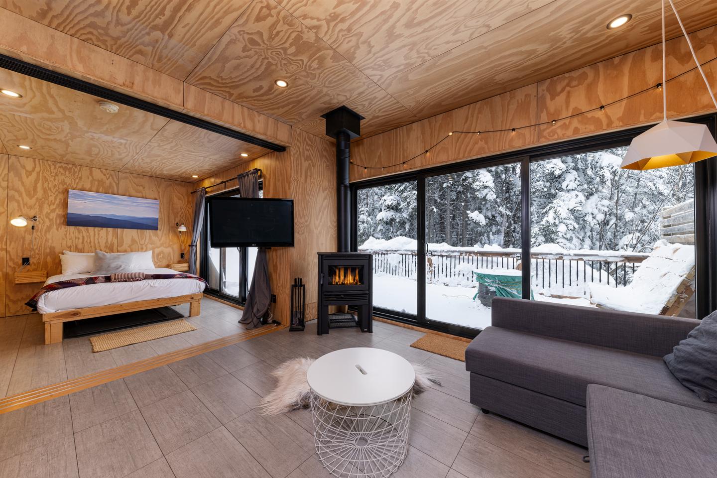Intérieur de chalet moderne avec cheminée et vue sur la neige.