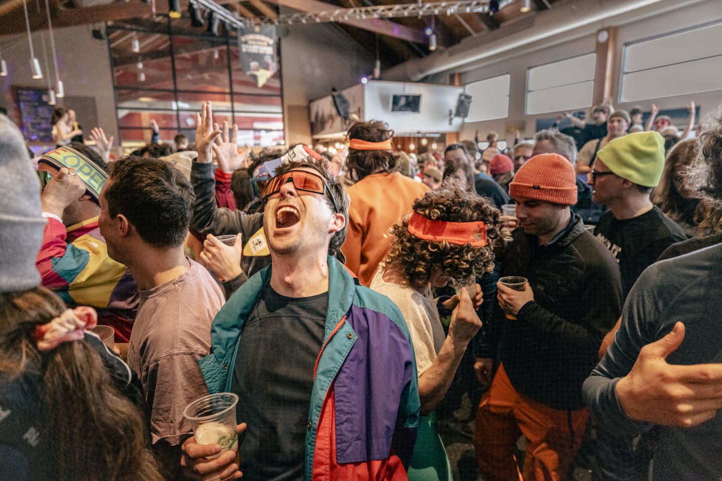 Foule festive en costumes colorés dans une salle animée.