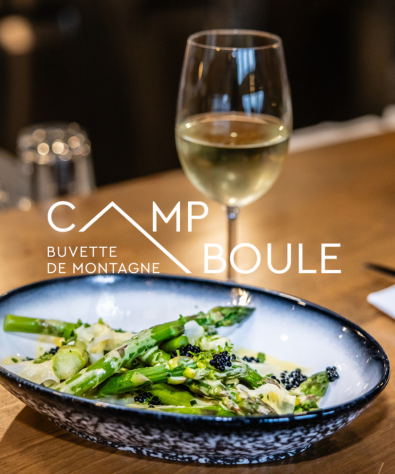 Assiette d'asperges et verre de vin blanc sur table en bois. Logo Camp Boule.