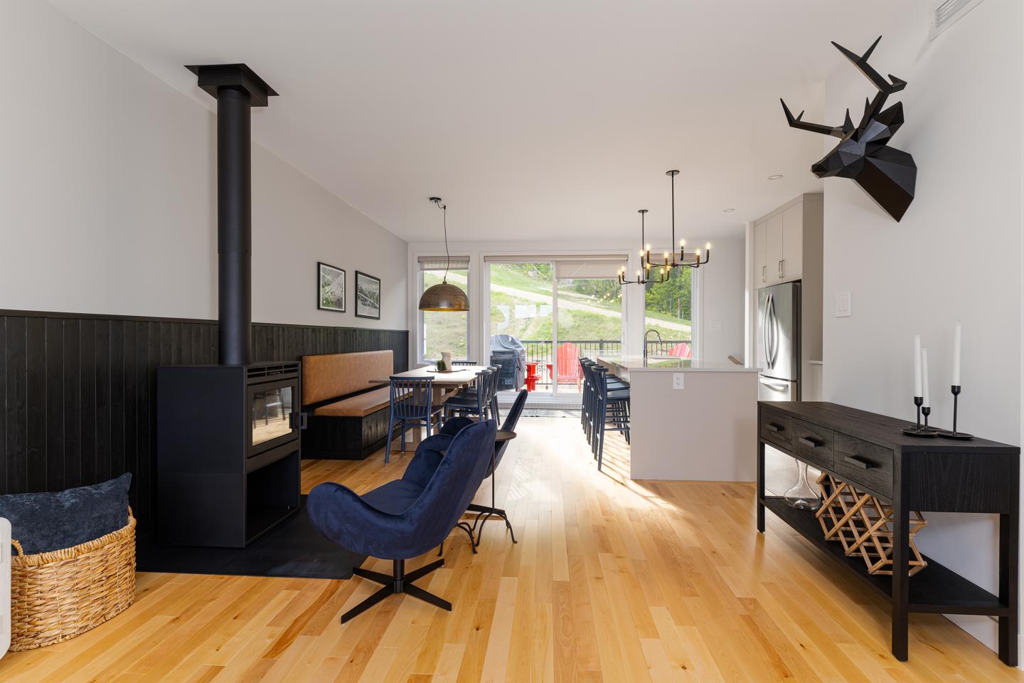Salon moderne avec cheminée, sol en bois clair, et chaise bleue. Décor minimaliste.