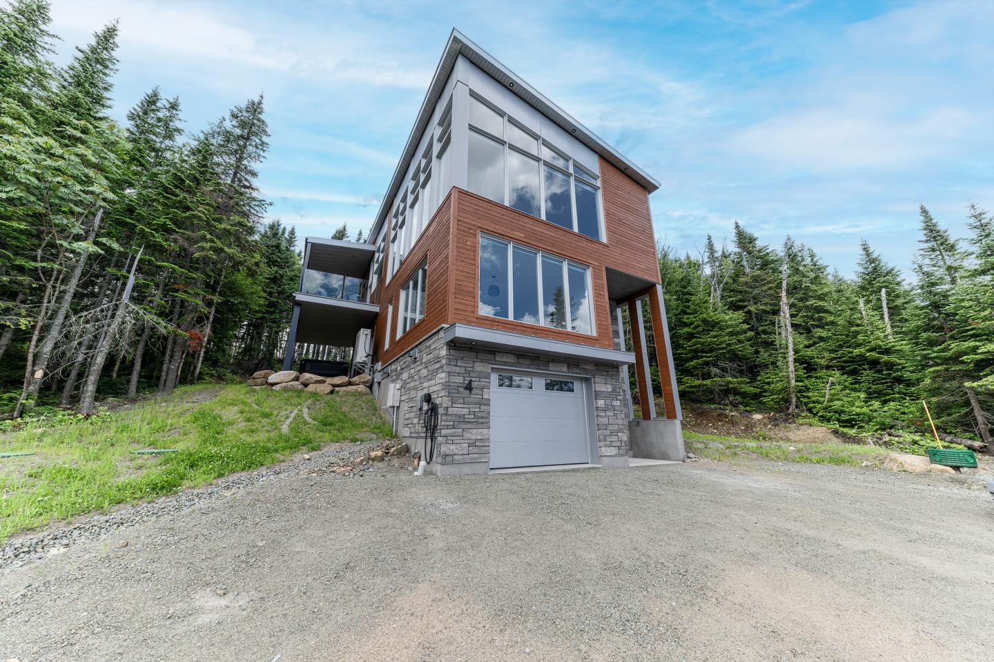Maison moderne entourée d'arbres, ciel bleu en arrière-plan.