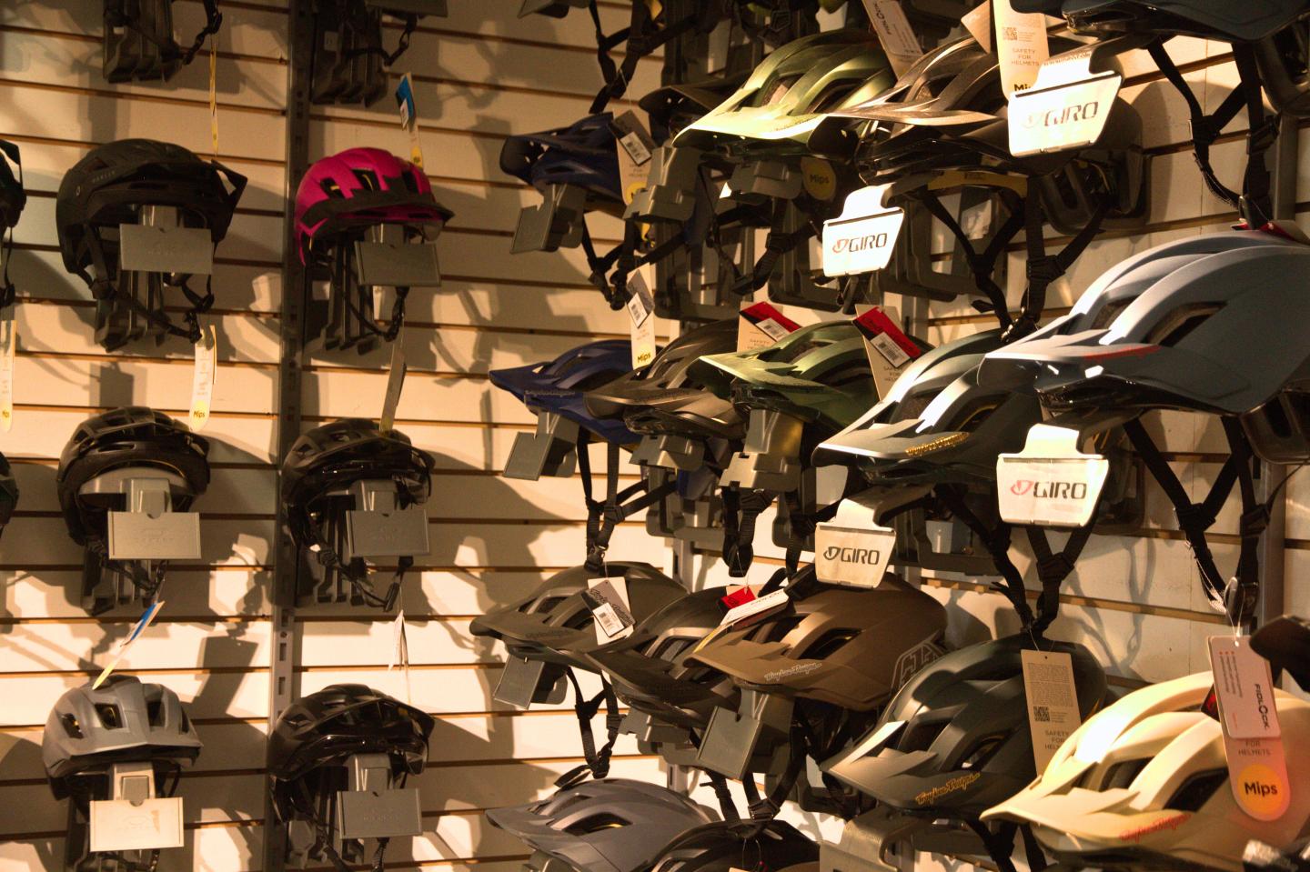 Casques de vélo de différentes couleurs accrochés à un mur.