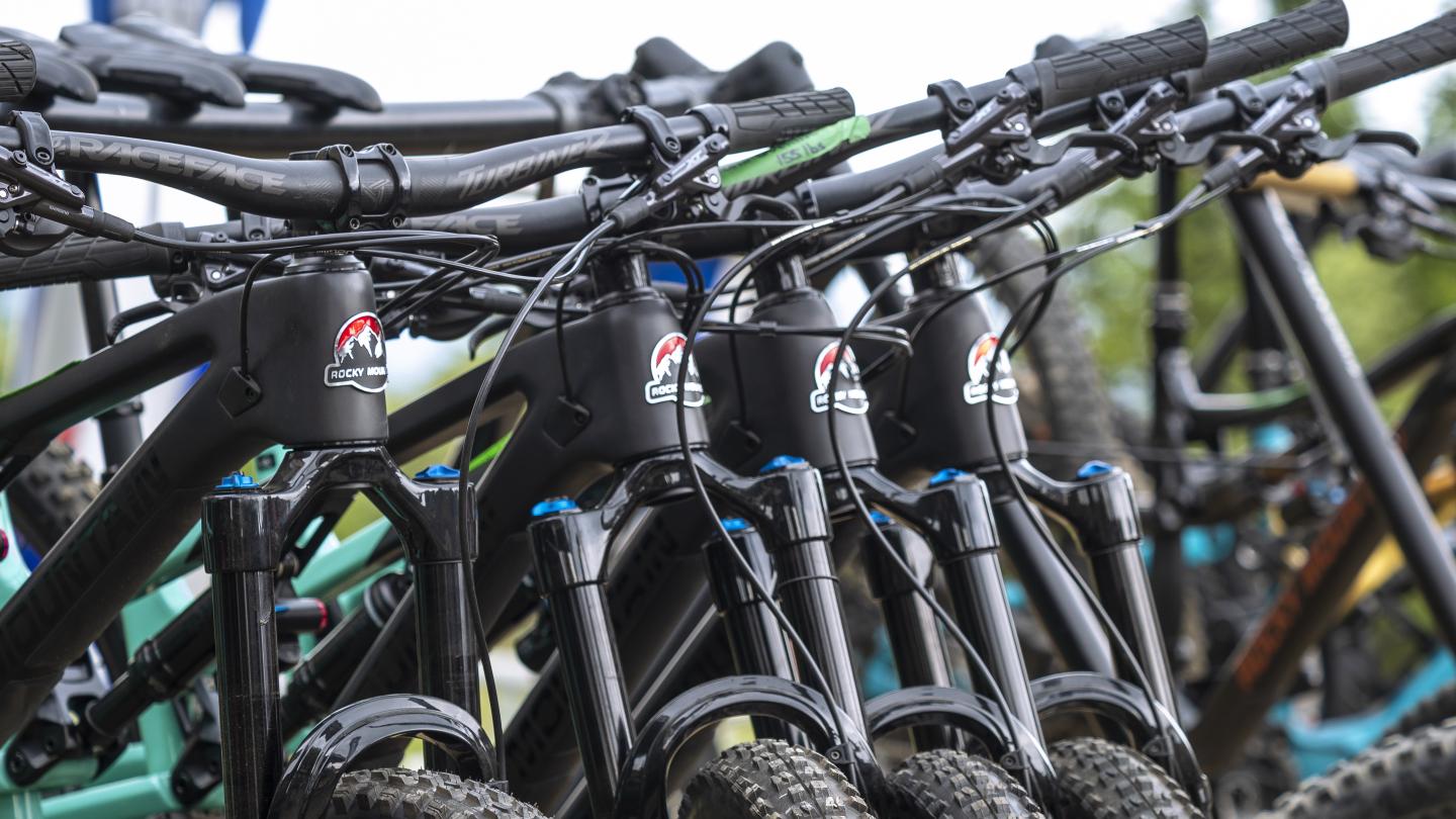 Plusieurs vélos de montagne alignés, pneus et guidons visibles.