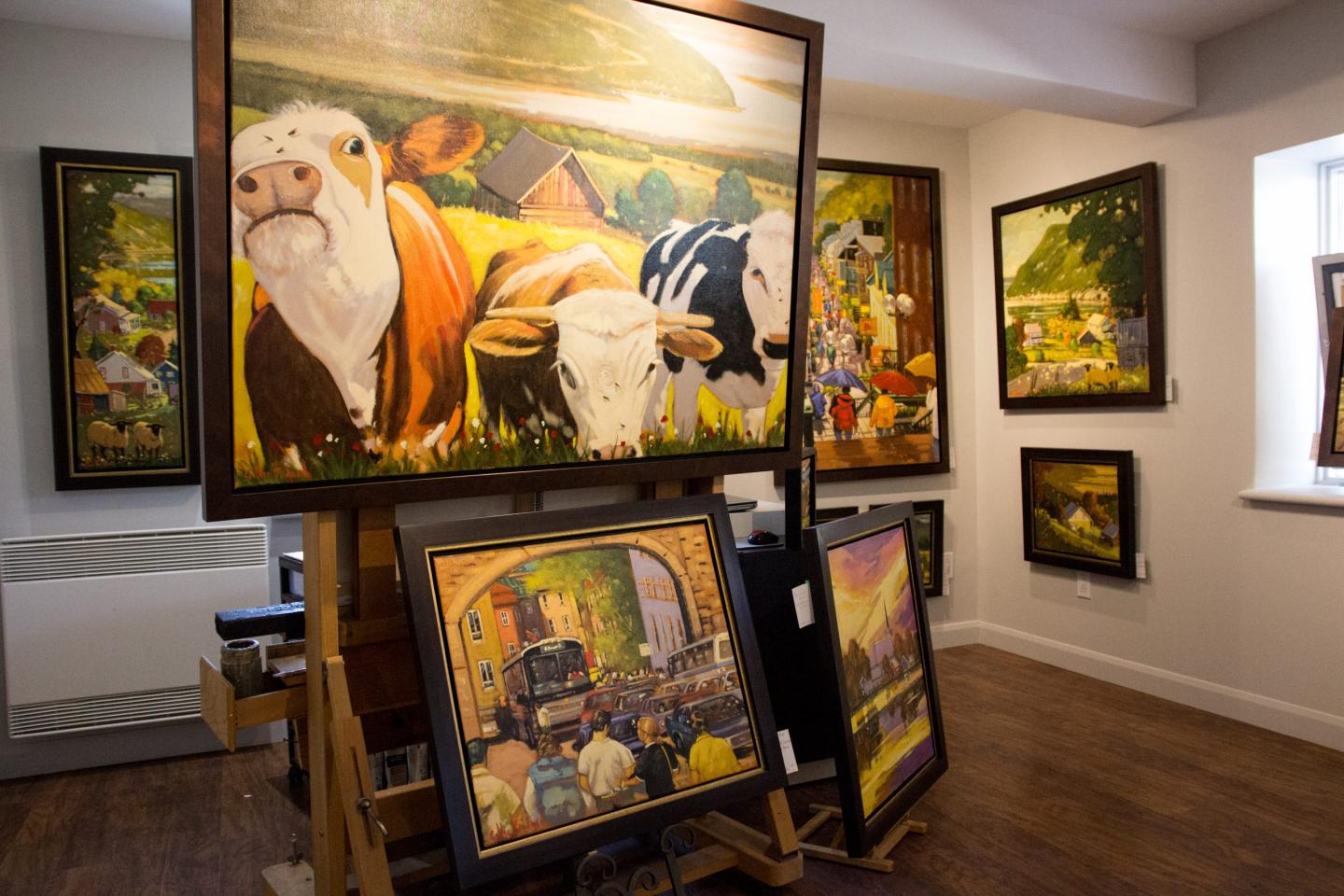 Galerie d'art avec peintures de vaches et paysages colorés.