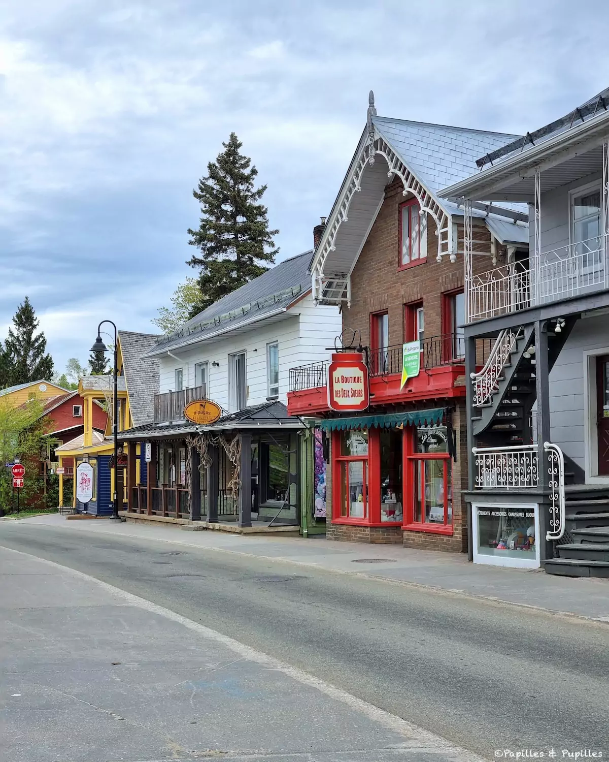Rue bordée de petites boutiques colorées sous un ciel nuageux.