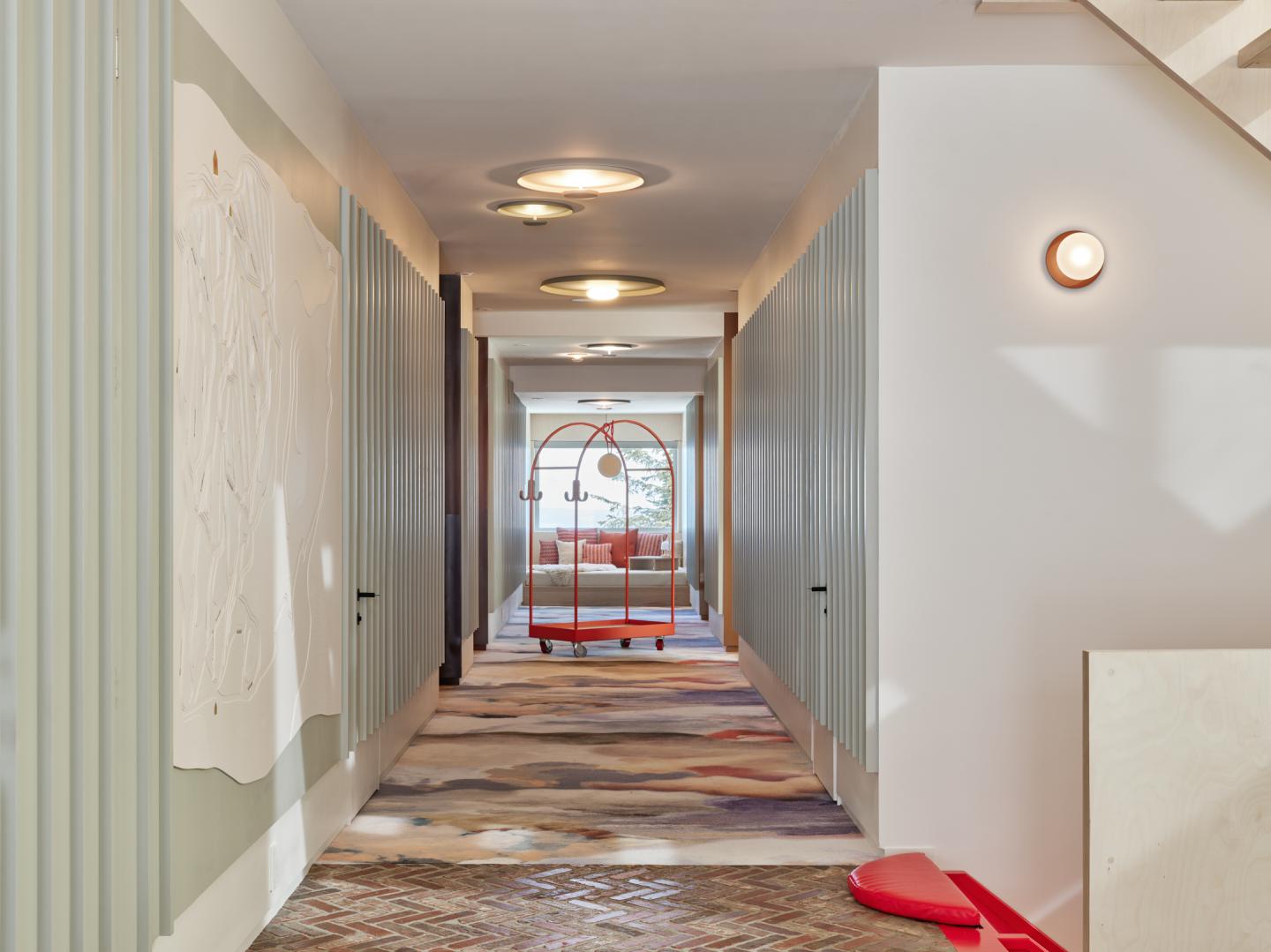 Couloir d'hôtel moderne avec chariot de bagages au fond.