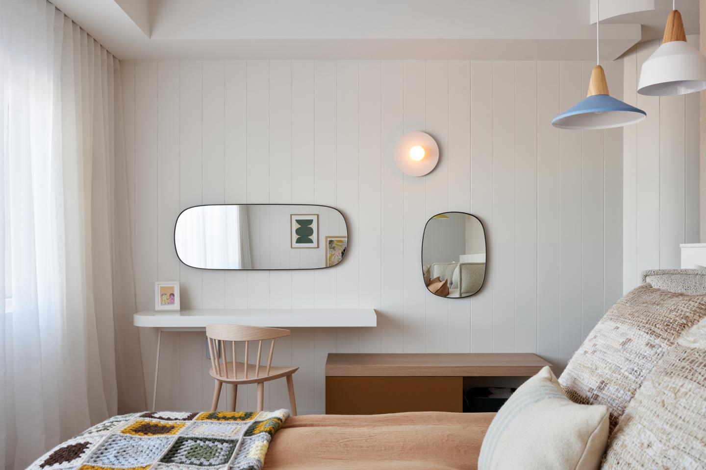Chambre moderne avec lit, bureau, miroirs et éclairage doux.