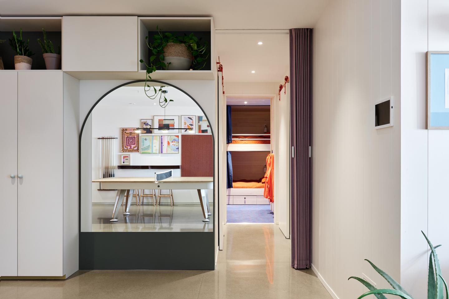 Intérieur moderne avec arches, bureau, et lit superposé coloré au fond.