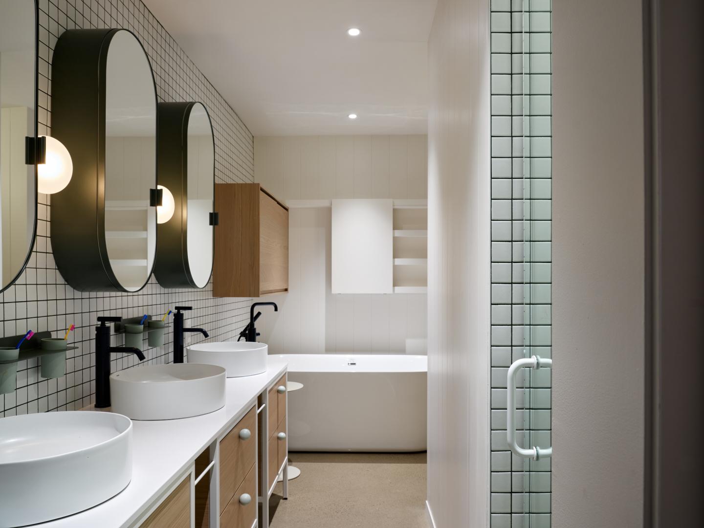 Salle de bain moderne avec double vasque et baignoire blanche.