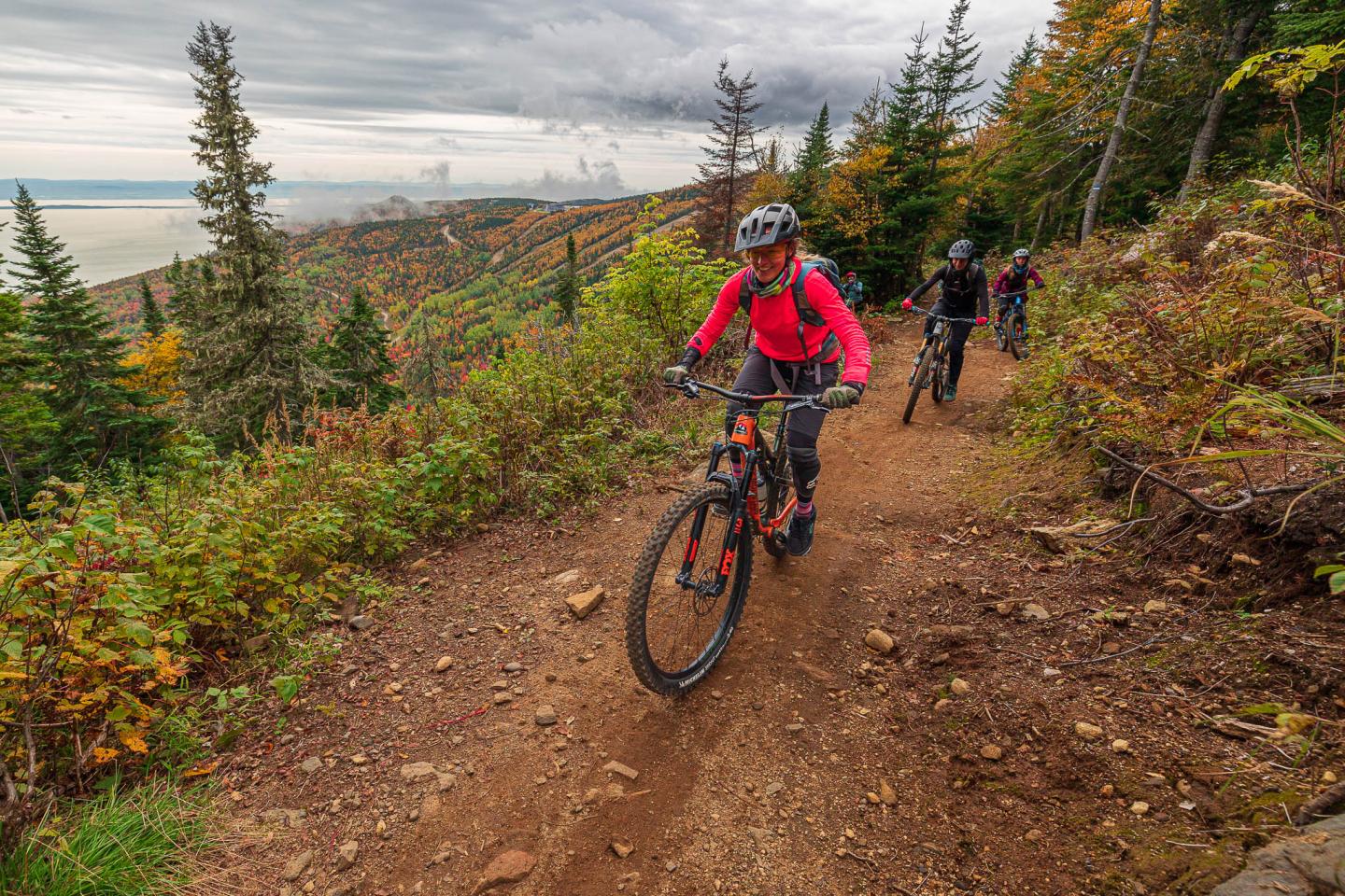 Famille en vélo de montagne sur un sentier forestier du Massif de Charlevoix avec couleurs d'automne