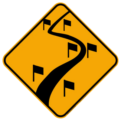 Panneau jaune avec route sinueuse et petits drapeaux.