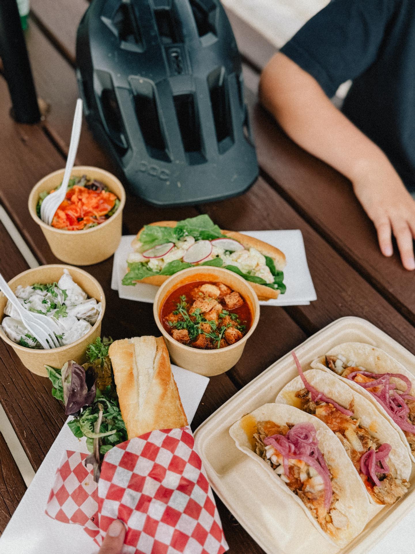 Tacos et bols de nourriture variés sur une table en bois avec un casque de vélo.