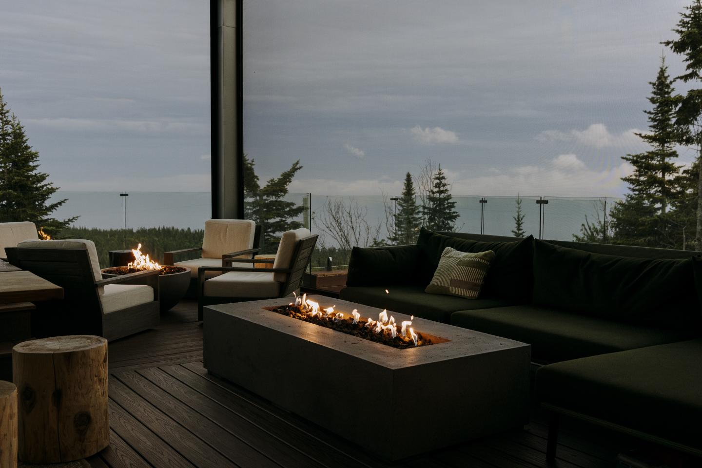 Terrasse avec vue sur mer, feu de table et fauteuils confortables.