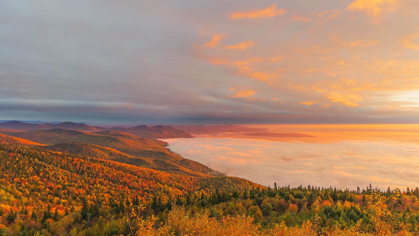 Paysage de montagne coloré au lever du soleil, ciel orangé.