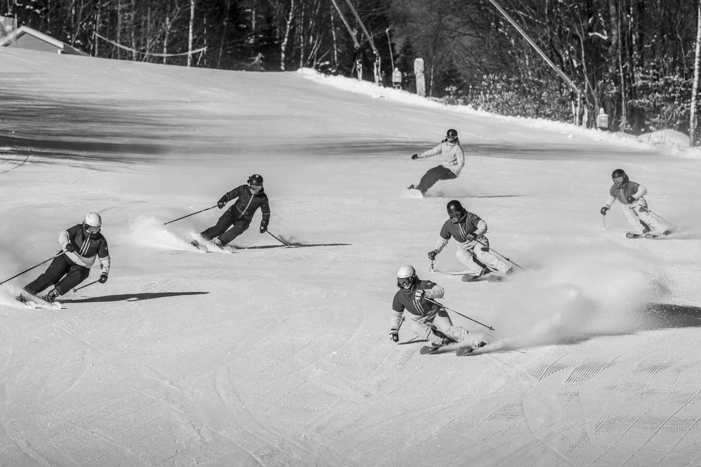 Skieurs dévalant une pente enneigée par temps clair.