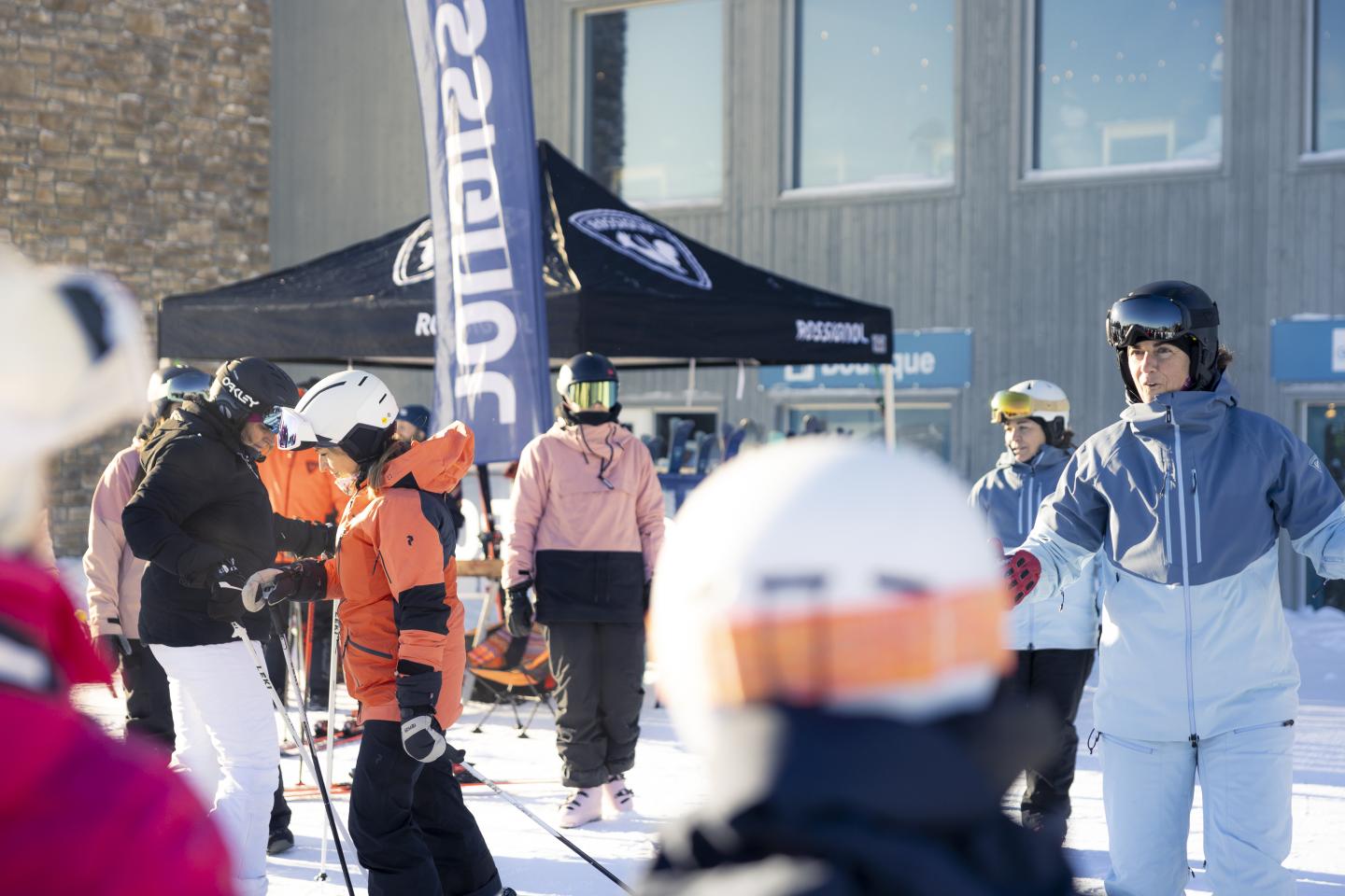 Des skieurs rassemblés devant un chalet sous un ciel ensoleillé.