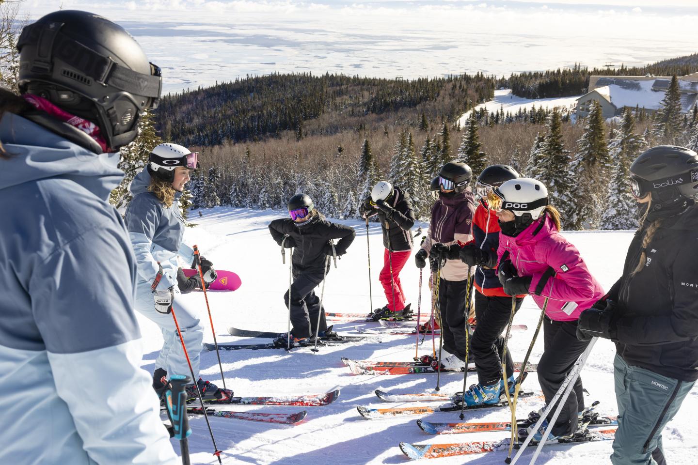 Groupe de skieurs discutant sur une pente enneigée sous un ciel dégagé.