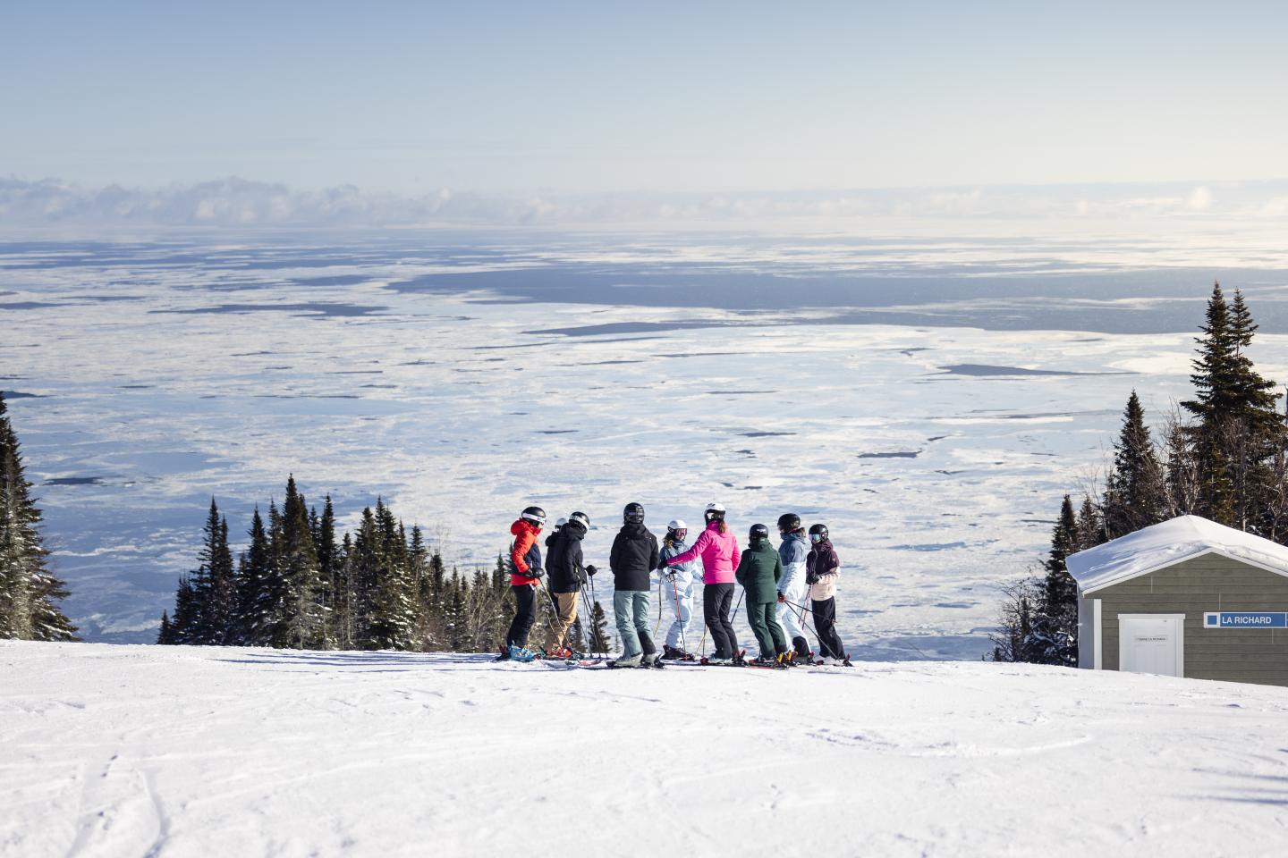 Groupe de personnes sur une piste enneigée avec vue sur un paysage hivernal.
