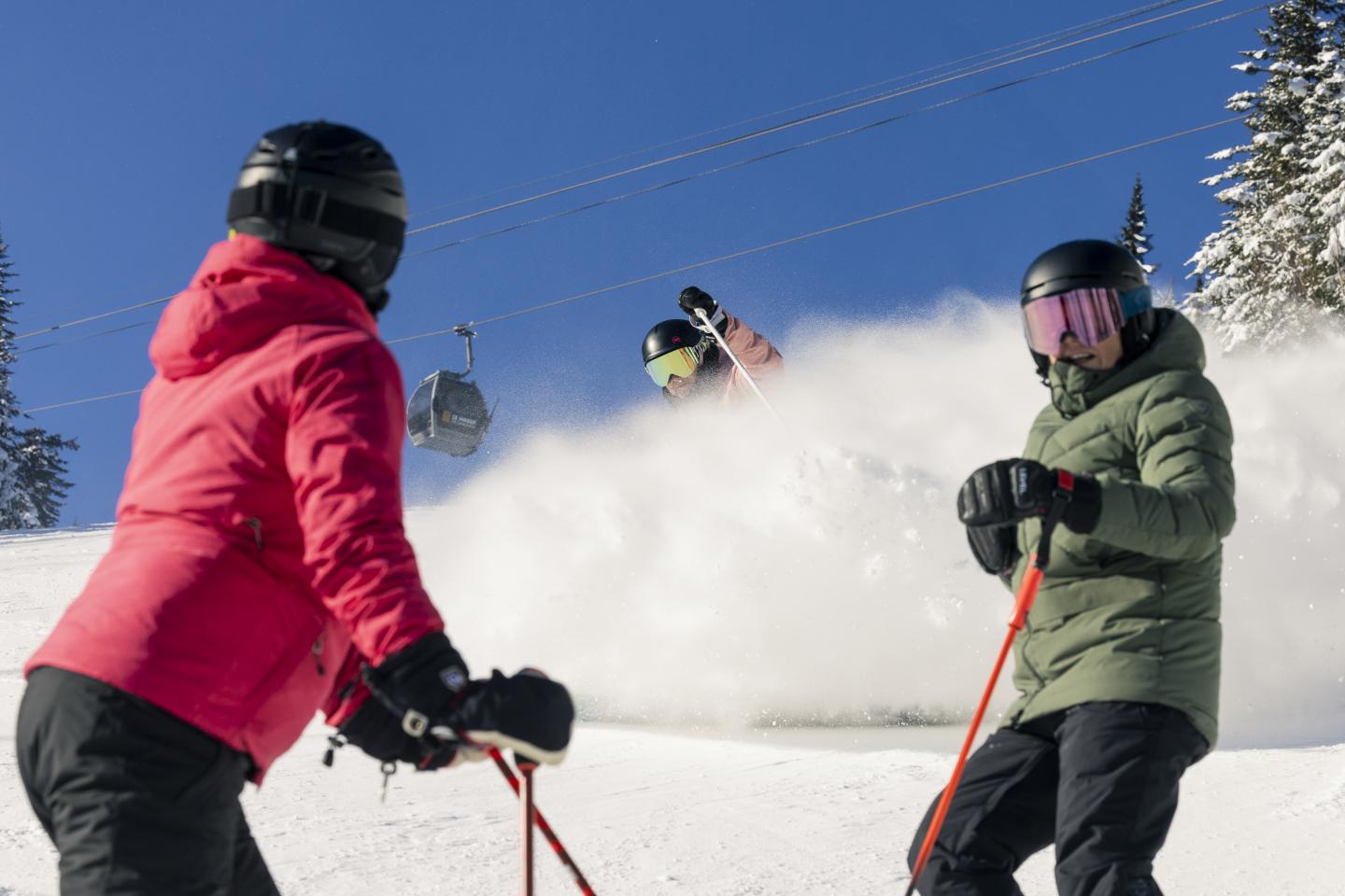 Des skieurs en tenue colorée sur une piste enneigée.