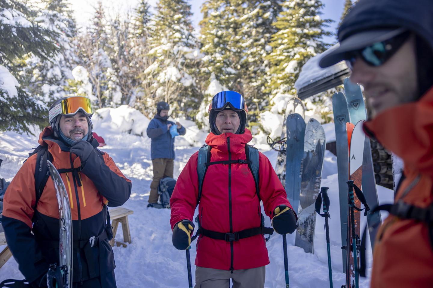 Deux skieurs en combinaison orange et rouge, forêt enneigée en arrière-plan.