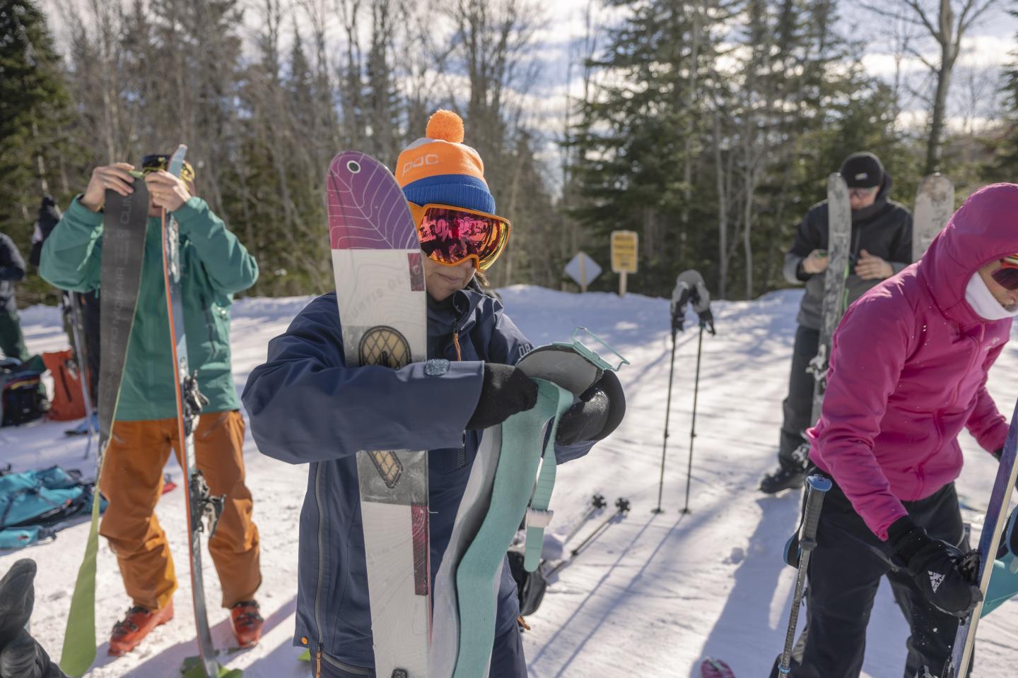 Des skieurs ajustent leur matériel sur la neige sous le ciel ensoleillé.