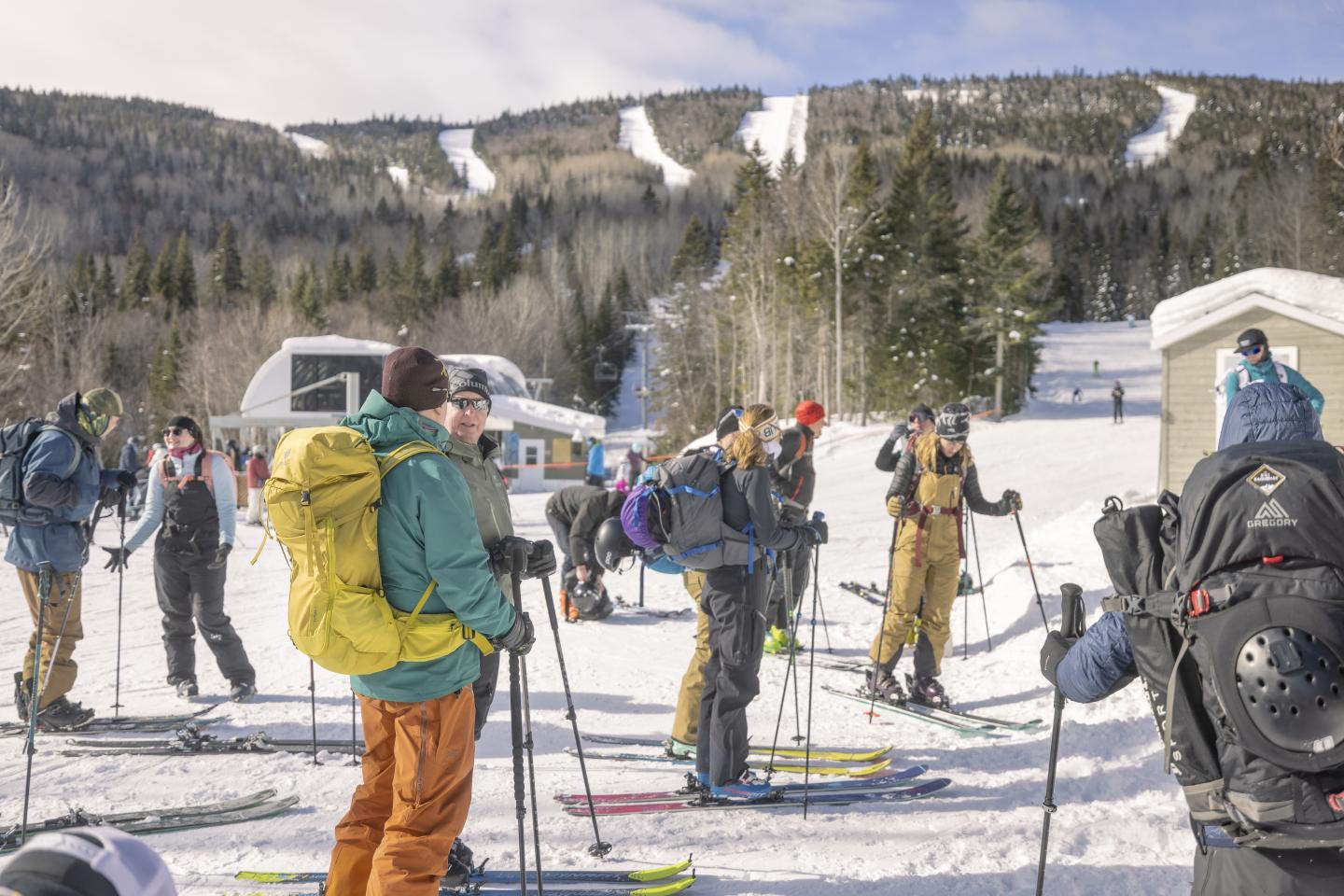 Groupe de skieurs à la station, équipés et prêts sur la neige sous un ciel bleu.