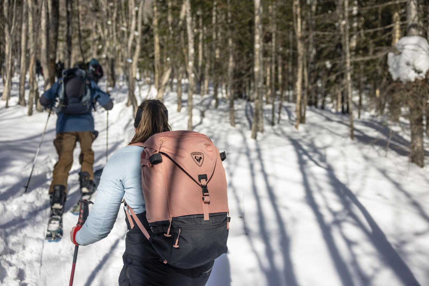Deux personnes font de la randonnée en raquettes dans une forêt enneigée.