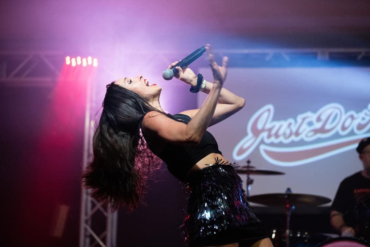 Chanteuse sur scène, micro en main, éclairage violet.