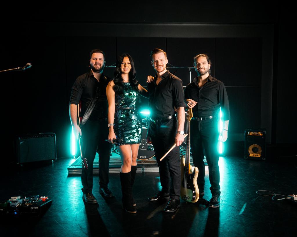 Groupe de musique en tenue noire dans une salle éclairée par des lumières vertes.