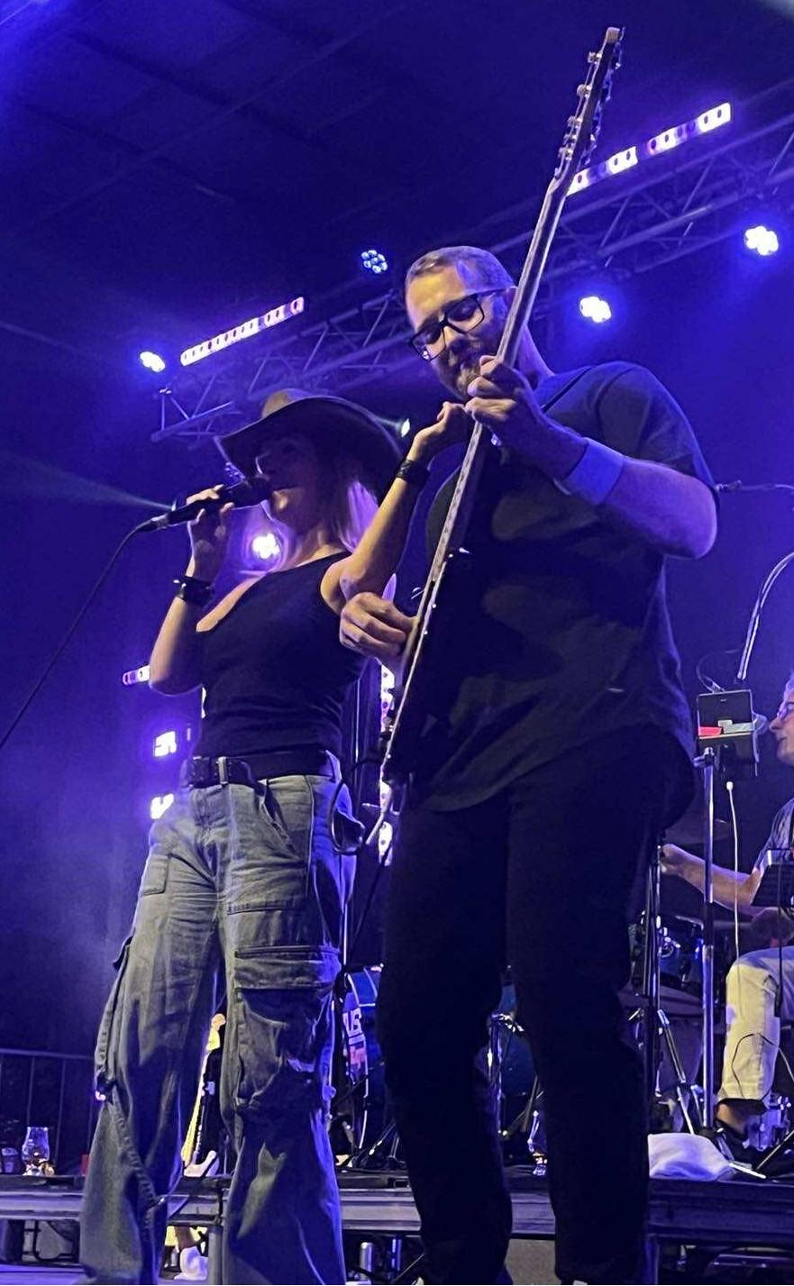 Groupe rock sur scène avec éclairage violet, chanteur et bassiste côte à côte.