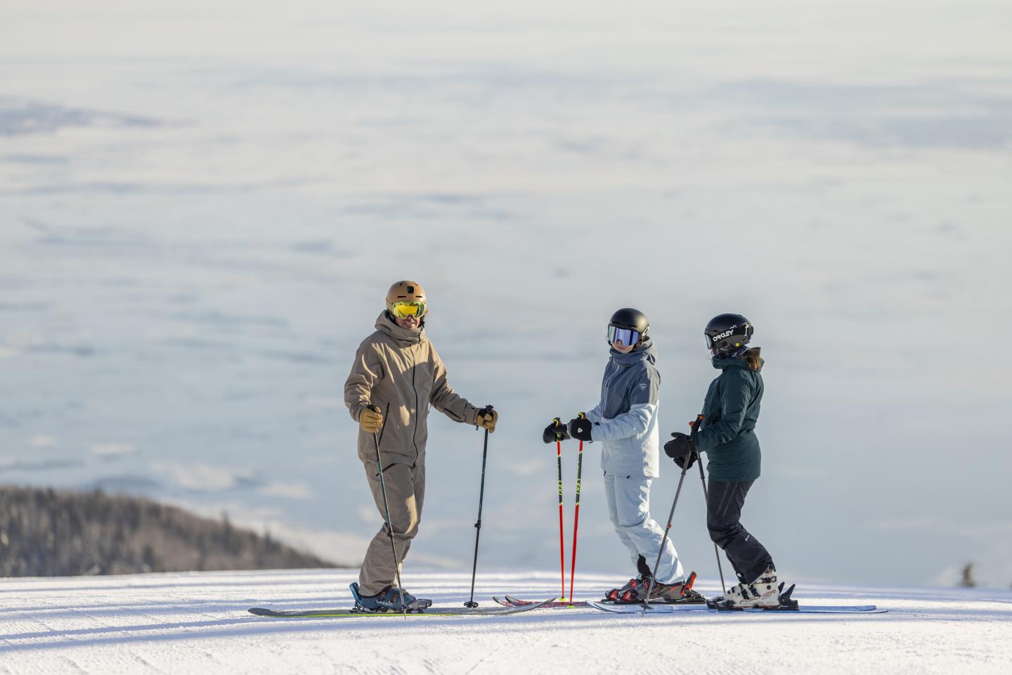 Trois personnes en ski discutent sur une piste enneigée.