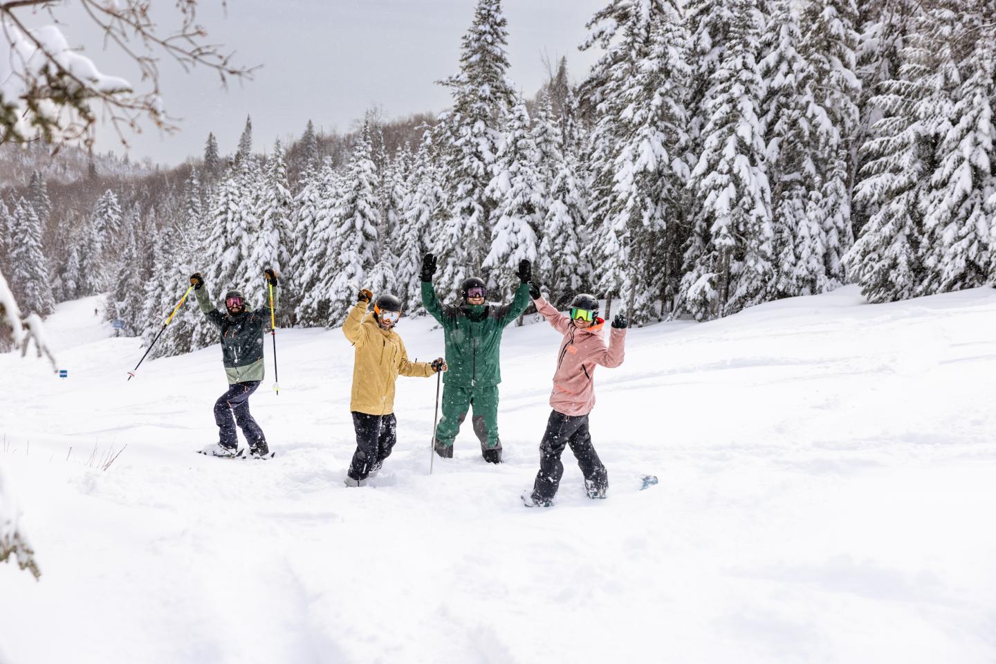 Groupe de skieurs souriants dans la neige, entourés de sapins enneigés.