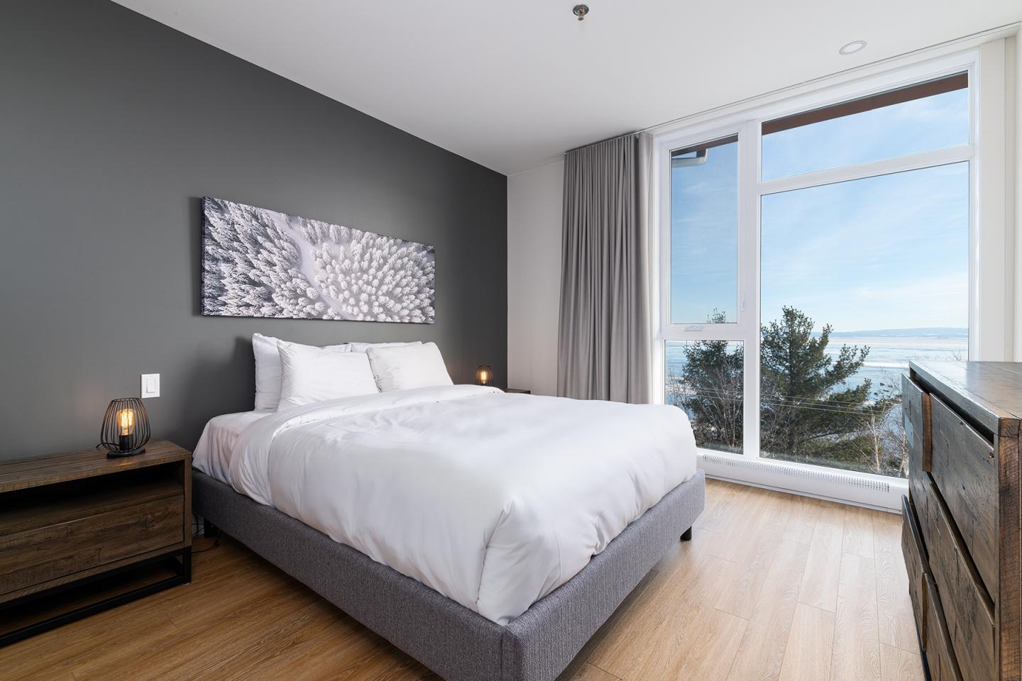 Chambre moderne avec lit double, grande fenêtre et vue sur la mer.