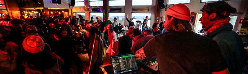 DJ mixant de la musique dans un bar animé, éclairage rouge et public dansant.