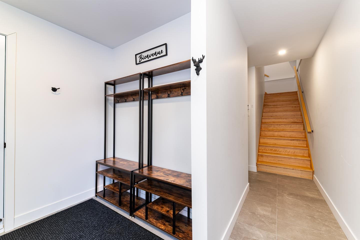 Couloir moderne avec escalier en bois et étagères en métal noir.