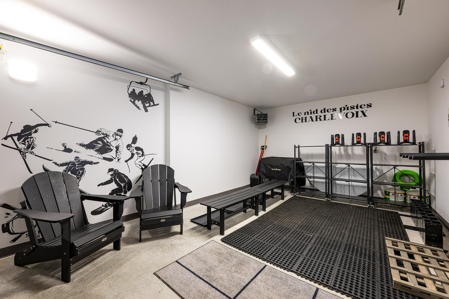 Garage moderne avec chaises, bancs, mur décoré de skieurs et rangement organisé.