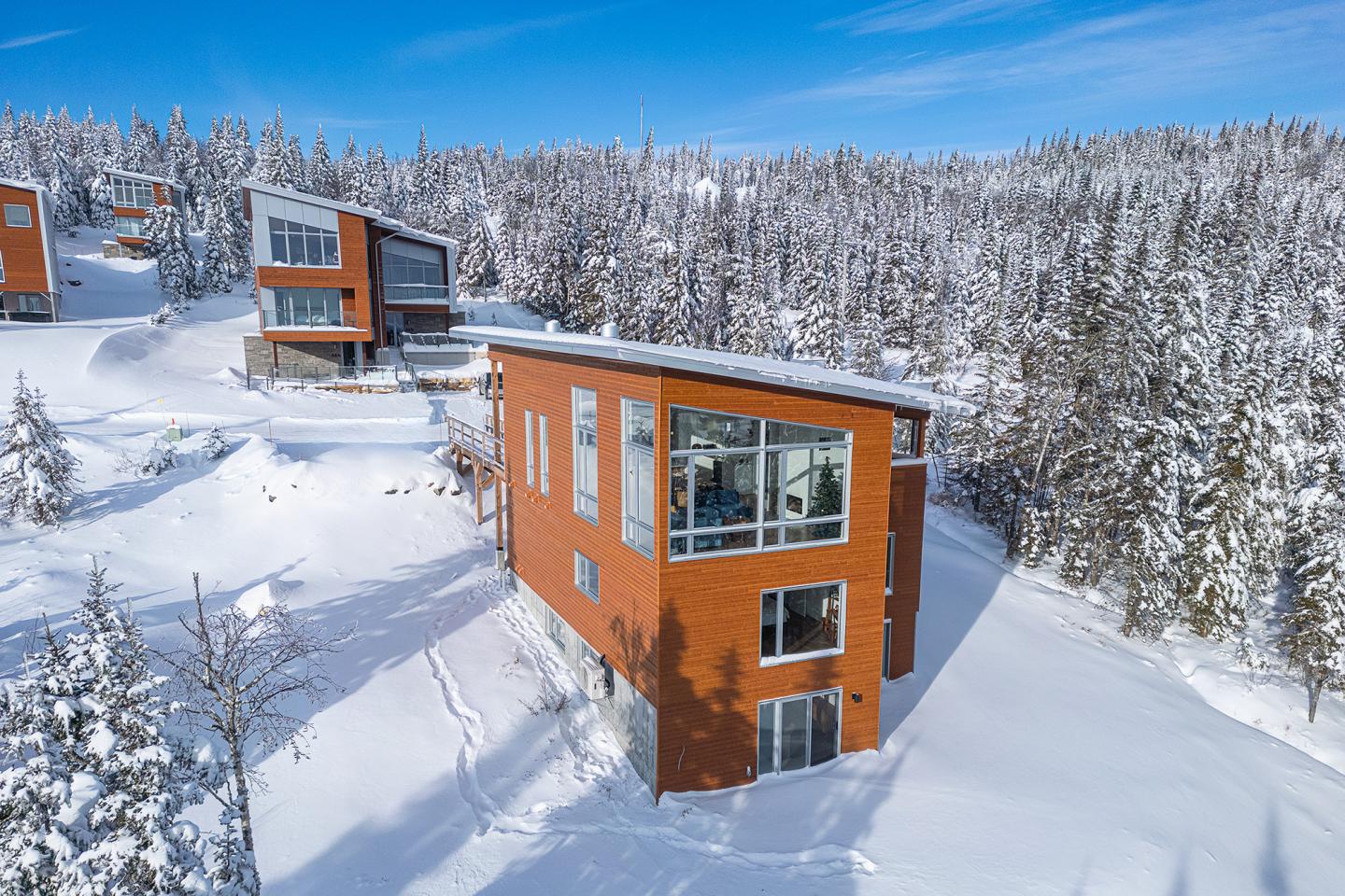 Chalets rouges entourés de neige sous un ciel bleu.