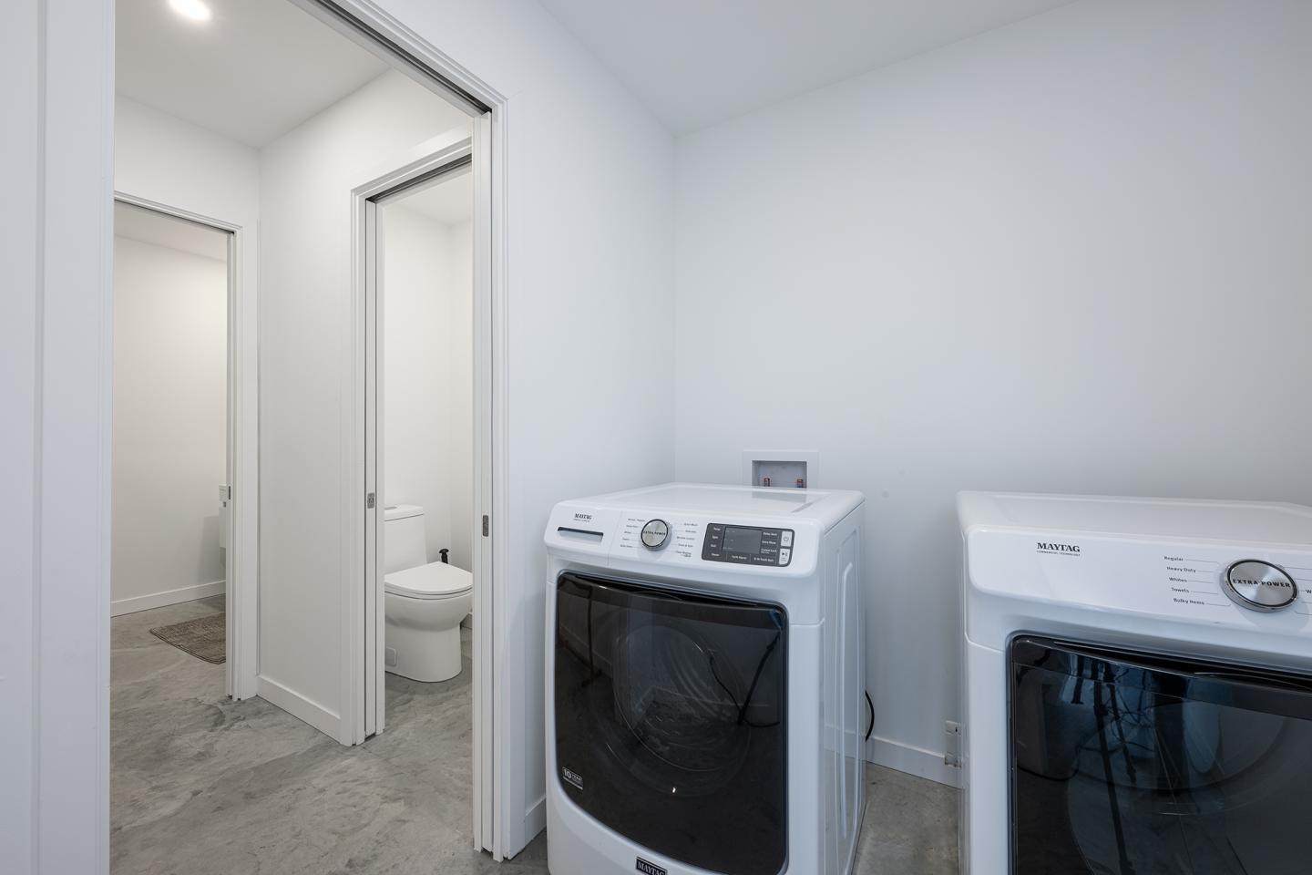 Buanderie moderne avec lave-linge et sèche-linge, sol gris.