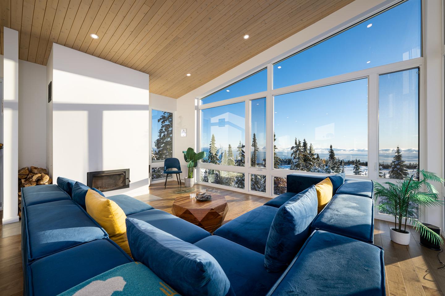 Salon moderne avec canapé bleu, baies vitrées, vue montagne.