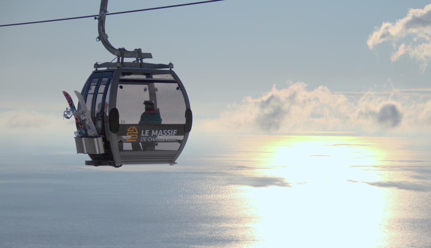 Téléphérique au-dessus de la mer, soleil couchant et ciel nuageux.