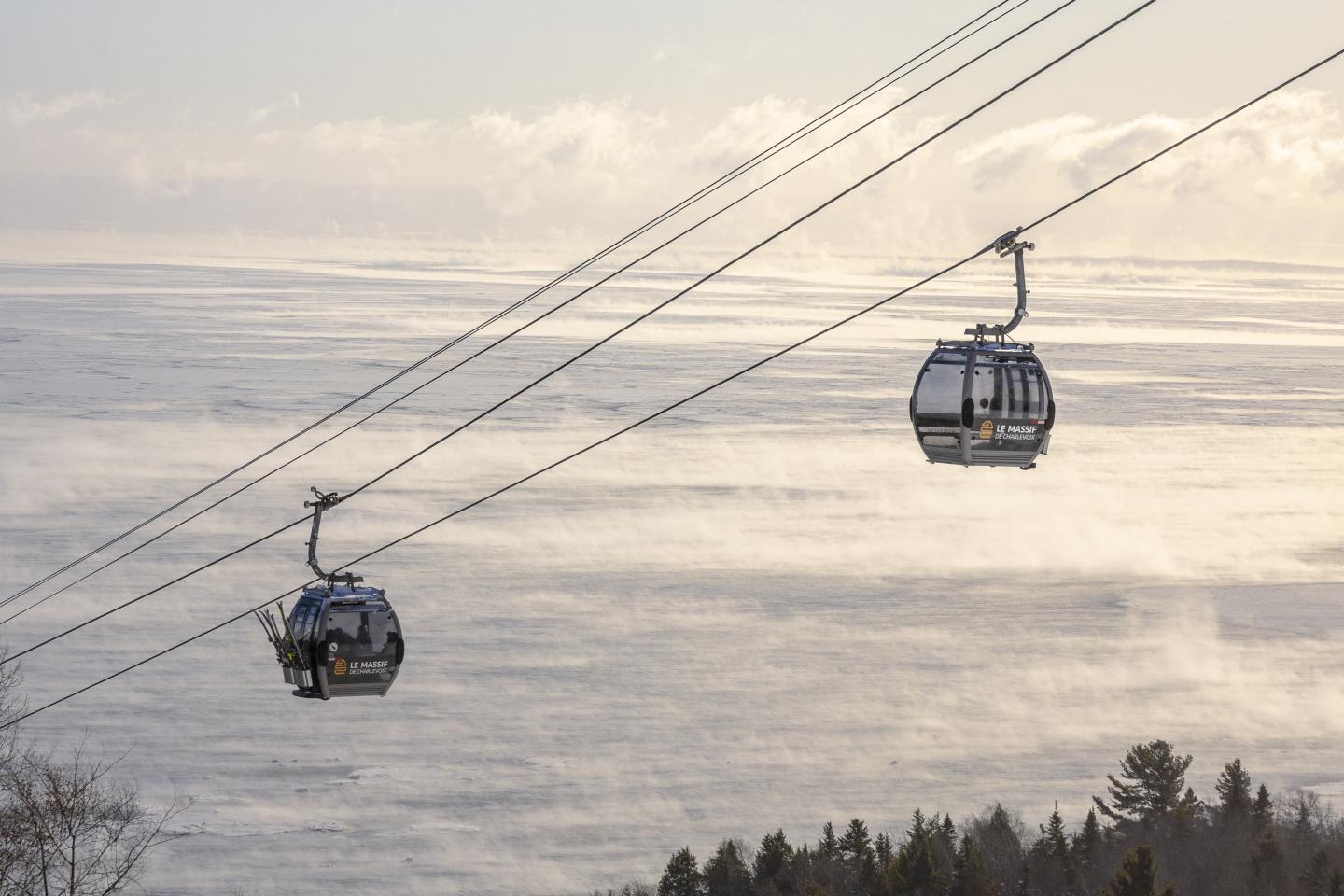 Téléphériques en surplomb d'un paysage de campagne enneigé, ciel nuageux.