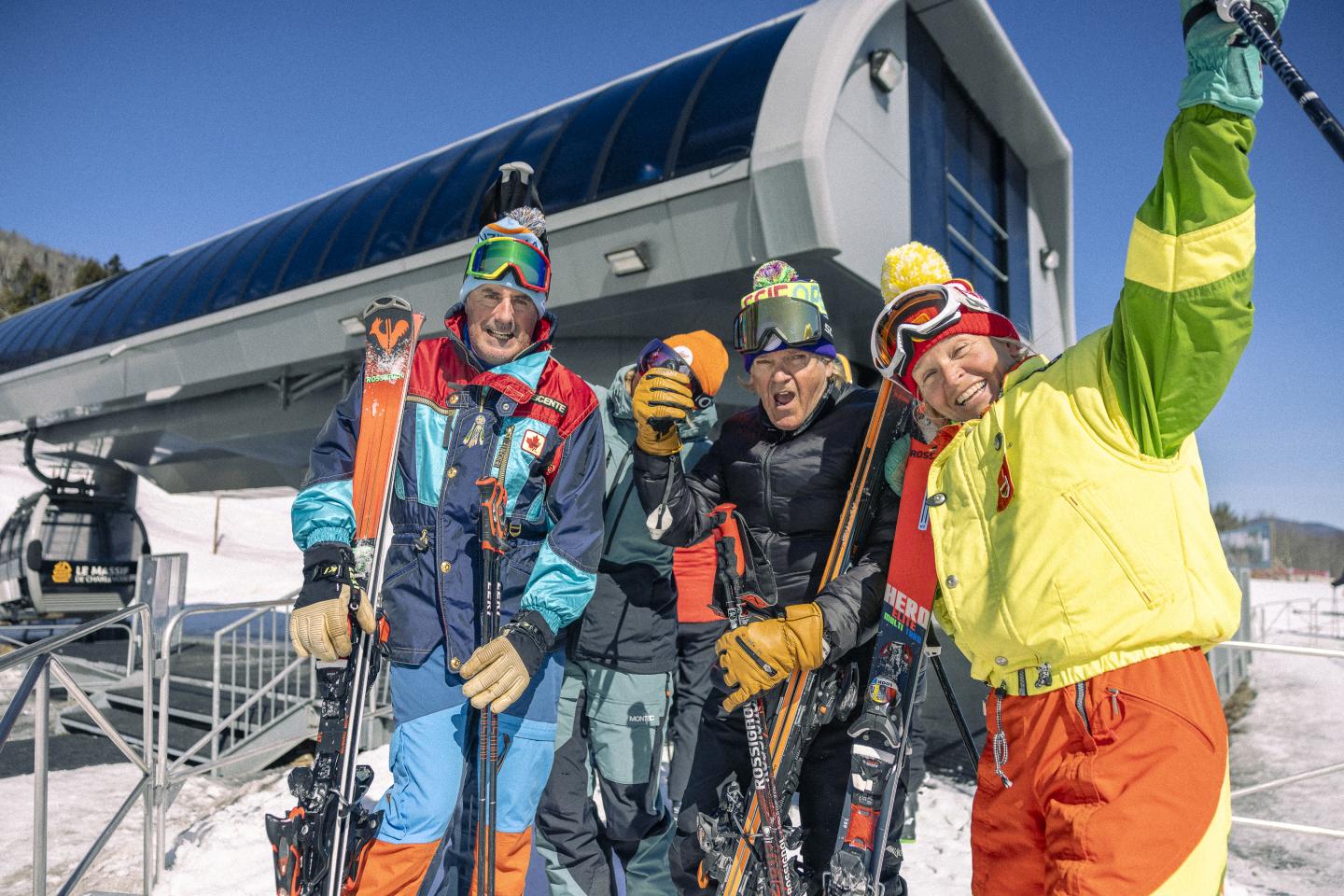 Quatre skieurs souriants devant un télésiège.