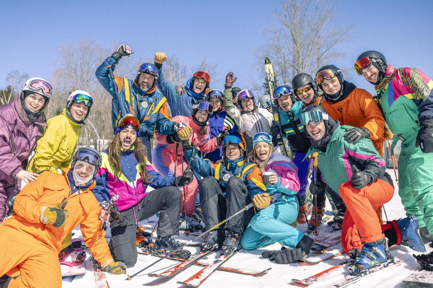 Un groupe de skieurs en tenues colorées sourit sur la neige.