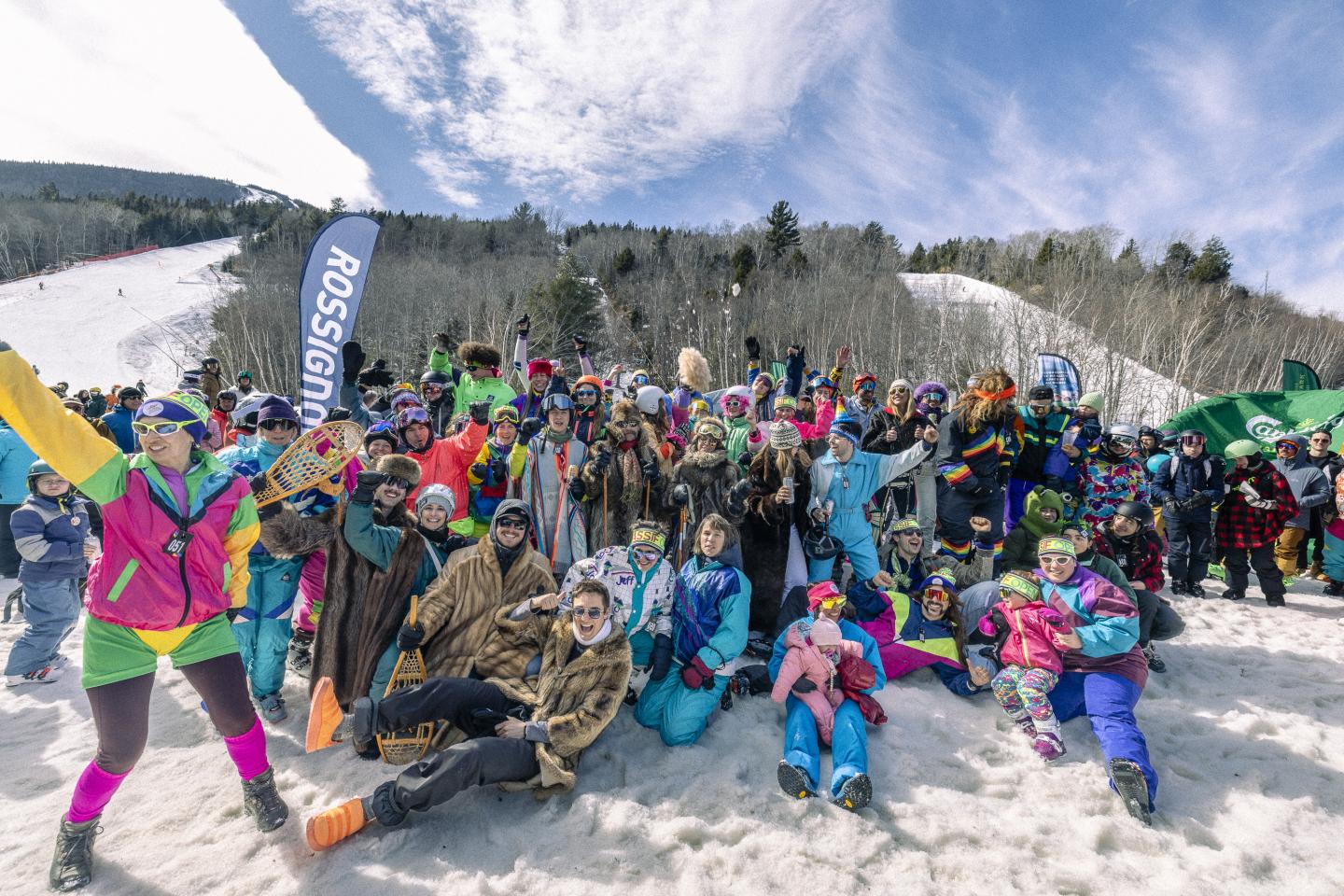 Groupe en vêtements colorés posant sur la neige sous un ciel bleu.
