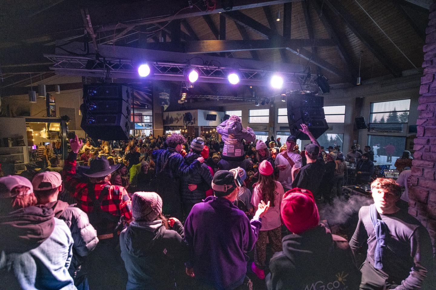 Foule applaudissant un concert dans une salle illuminée de lumières colorées.