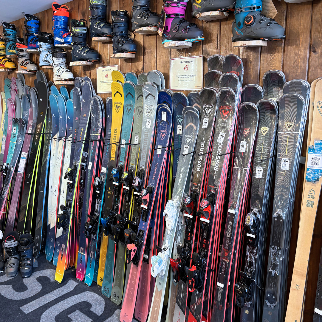 Skis et chaussures de ski colorés alignés sur un mur en bois.