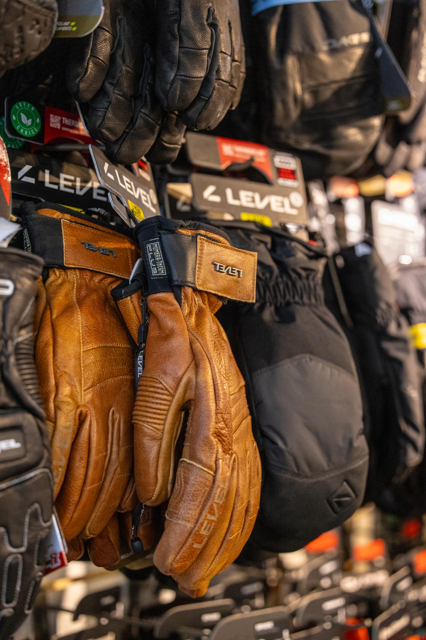 Gants de moto en cuir marron et noir accrochés à un présentoir.