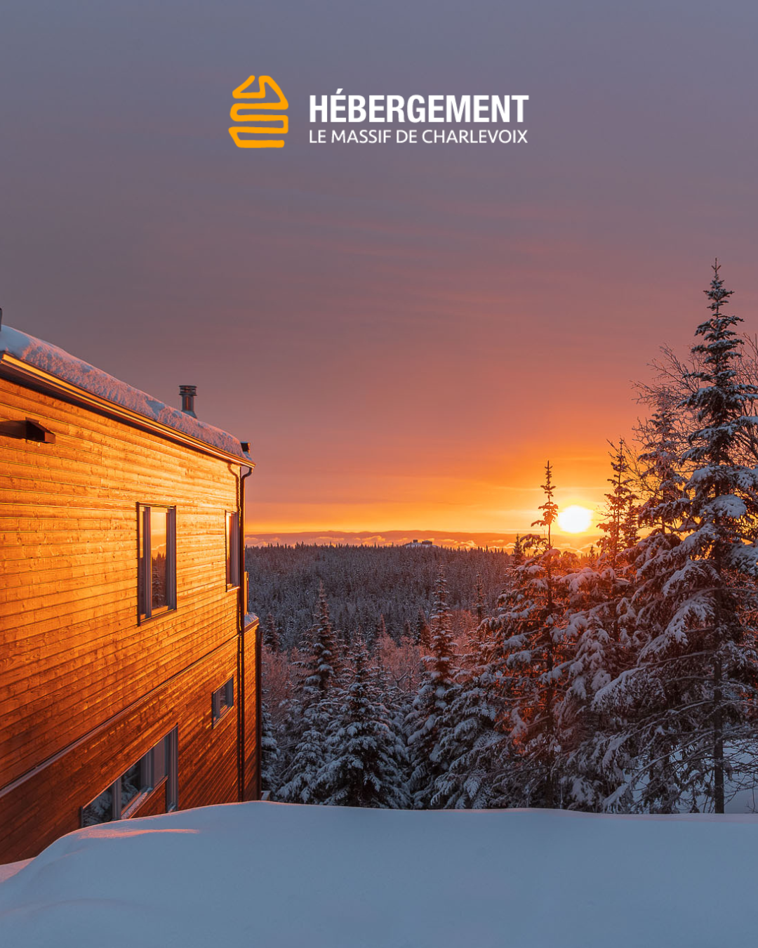 Chalet en bois au coucher du soleil, entouré de sapins enneigés.