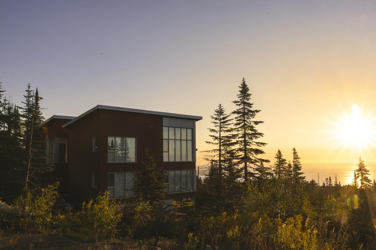 Maison moderne au bord d'une forêt au coucher du soleil.